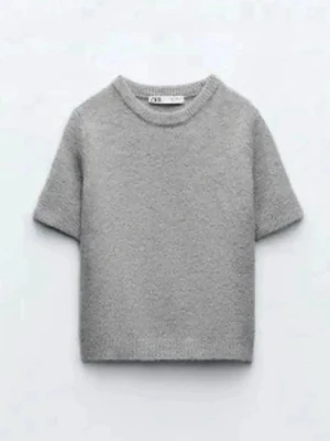 Grå stickad topp Zara - Superfin grå stickad topp från Zara med korta ärmar och rund hals. Enkel och stilren design som passar perfekt till jeans eller kjol. Mjuk och skön kvalitet som känns lyxig mot huden.