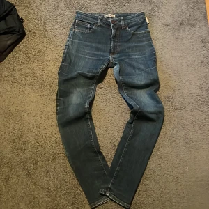 Vintage Acne Jeans straight fit - Säljer ett par mörkblå jeans från Acne Jeans med klassisk femficksdesign och orange kontrastsömmar. Jeansen har en rak passform och normal midja, tillverkade i slitstarkt denimtyg. Perfekta för dig som gillar stilrena och tidlösa jeans. Pris kan diskuteras vid snabb affär!