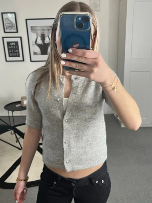 Grå Gina kofta - Knappt använd kofta från Gina med silvriga knappar! Perfekt nu till sommaren. Är i storlek 146/152 men passar mig som egentligen har  XS/S. Kom gärna med prisförslag
