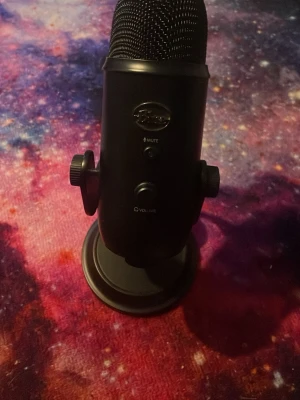 Svart Blue Yeti USB-mikrofon - Säljer en svart Blue Yeti USB-mikrofon med metallkropp och stabilt stativ. Mikrofonen har volymkontroll, mute-knapp och flera inspelningslägen. Perfekt för streaming, podd eller gaming. Snygg och robust design som passar på skrivbordet.