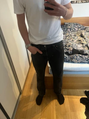 Svarta raka jeans från Levi's - Säljer ett par svarta jeans från Levi's med rak passform och klassisk femficksdesign. Jeansen har normal midja och är tillverkade i ett slitstarkt denimtyg. Perfekta för dig som gillar en clean och tidlös stil. Några stygn på lappen back har losnat kolla bild 3. Hör av er vid frågor 