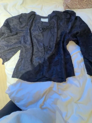 Mörkblå blus från Neo Noir - Snygg mörkblå blus från Neo Noir med subtilt mönster och knytband framtill. Blusen har långärmad design och är tillverkad i ett lätt, transparent material som ger en cool och trendig look. Perfekt att matcha med jeans eller kjol. Nypris ca 900 kr