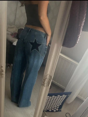 Blå jeans med stjärndetalj bak - Säljer ett par blå jeans med rak passform och en mörkblå stjärna som detalj på bakfickorna. Jeansen är i strl 38, men skulle säga att de passar 38/40. Verkligen världens snyggaste jeans men kommer tyvärr inte till användning för min del💕