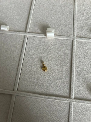 Guldigt hjärtörhänge från Muli Collection - Snyggt berlock i guldton från Muli Collection med ett litet hängande hjärta. Örhänget har en enkel och stilren design som passar perfekt till alla tillfällen. Tillverkat i metall med blank finish och vattenavvisande egenskaper.