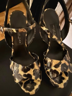 Leopardmönstrade sandaler Philipp Plein - Snygga pumps med platå och höga klackar från Philipp Plein. Remmar som korsar över foten och runt vristen. Perfekta för dig som vill sticka ut och addera edge till din outfit.