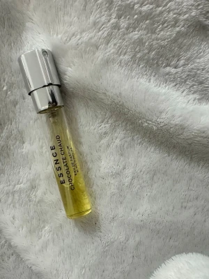 Essnce Chocolat Chaud parfym - En smidig parfym från Essnce med doften Chocolat Chaud. Flaskan är genomskinlig med gulaktig vätska och har en stilren, silverfärgad spraykork. Perfekt att ha med i väskan för en söt och varm doftupplevelse.