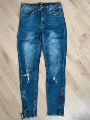 Blå slitna jeans med dragkedjor - Se bilder