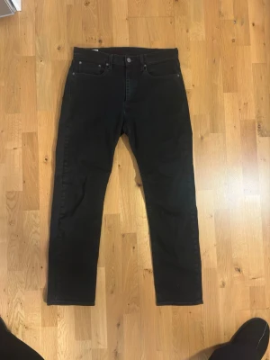 Svarta jeans från Levi's Premium - Säljer ett par svarta jeans från Levi's Premium med klassisk femficksdesign och raka ben. Jeansen är tillverkade i stretchigt material för extra komfort och har en stilren look som passar till det mesta.