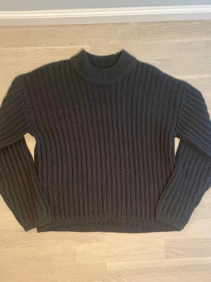 Mörkgrå grovstickad tröja oversized | KAFFE | L/40 | Ny - Grovstickad pullover från KAFFE med mock-neck och avslappnad oversized passform. Obs — storlekslappen är borta, storleken är uppskattad utifrån måtten (axel 58 cm, längd 60 cm). Märke: KAFFE Storlek: L/40 Färg: Mörkgrå Material: 50% Bomull / 50% Akryl Skick: Helt ny, aldrig använd Ordinarie pris: 399 SEK
