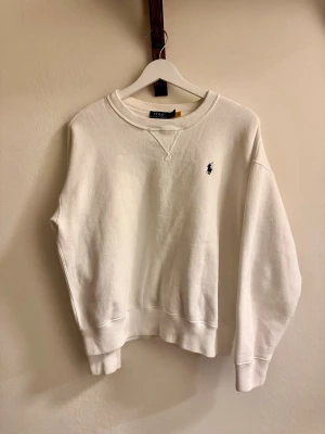 Vit sweatshirt från Polo Ralph Lauren -  vit sweatshirt från Polo Ralph Lauren med rund halsringning och ribbade muddar. Storleken är M, dock tycker jag att den mer är som S! 