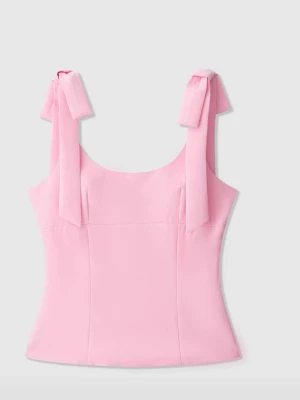 Rosa linnetopp med rosetter - helt oanvänd. Supersöt ljusrosa linnetopp med breda axelband som knyts i stora rosetter. Toppen har en figurnära passform och är perfekt för varma dagar. Tillverkad i ett mjukt syntetmaterial som känns bekvämt mot huden.