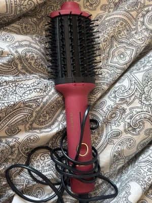 Rund fönborste från Glamorous - Elektrisk rund fönborste i matt mörkrosa färg med svarta borst och detaljer. Perfekt för att styla och torka håret samtidigt. Ergonomiskt handtag och enkel knapp för att slå på och av. Sladd för elanslutning.