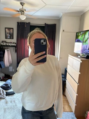 Vit sweatshirt med rund hals - En enkel och stilren vit sweatshirt med rund hals och ribbade muddar vid ärmslut och nederkant. Perfekt för en avslappnad look och passar bra till jeans. 