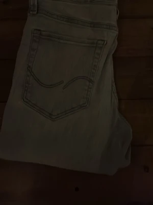 Ljusgrå raka jeans - Snygga ljusgrå jeans med klassisk femficksdesign och raka ben. Jeansen har en enkel bakficka med dekorativ söm och är perfekta för en avslappnad stil. Tillverkade i denim med en mjuk känsla.