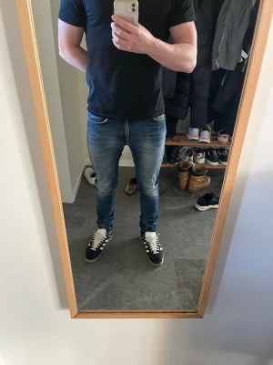 Nudie Jeans Lean Dean - Nudie Jeans i modellen Lean Dean. Ett par jeans med mycket användning och därav de unika och snygga slitningarna. Jeansen är i fint skick, men en defekt är att de är lagade mellan benen i nudies egna butik. Jag är 175 och väger 70kg.