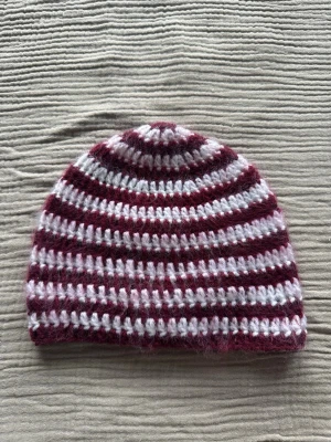 Virkad mössa - Egentillverkad virkad mössa i vitt och vinrött garn. Mössan är borstad så att den ser fluffig ut. Tvättas i max 30 grader