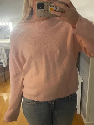 Ljusrosa stickad tröja - Mysig ljusrosa stickad tröja med rund halsringning och långa ärmar. Tröjan har en enkel och avslappnad passform med ribbade muddar vid ärmslut och nederkant. Perfekt att matcha med jeans för en chill look.