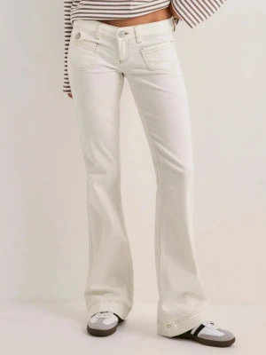 Vita bootcut jeans med kontrastsömmar - Säljer ett par vita bootcut jeans från NELLY med snygga kontrastsömmar. Jeansen har låg midja och utsvängda ben för en trendig siluett. Helt nya , säljer pga fel storlek.  
