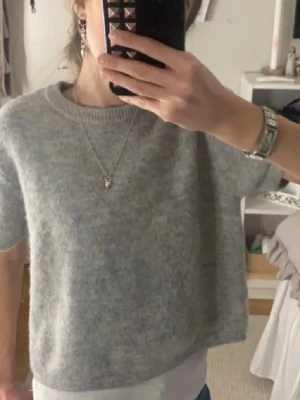 Grå stickad tröja Gina Tricot - Mysig grå stickad tröja från Gina Tricot med korta ärmar och rund halsringning. Tröjan har en enkel och stilren design, perfekt att matcha med olika outfits. Materialet är mjukt och ger en avslappnad look. Mkt bra skick!💕🫰🫰