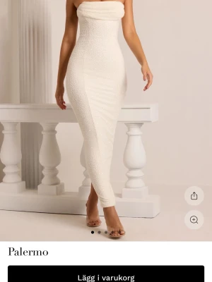 Vit långklänning med pärlor Palermo - Elegant vit långklänning från Palermo med figurnära passform och axelbandslös design. Klänningen är dekorerad med små pärlor över hela tyget för en exklusiv look. Perfekt för dig som vill sticka ut med en unik och lyxig stil.