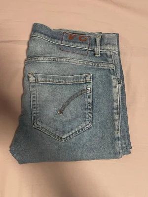 Dondup jeans - Säljer ett par ljusblå jeans från dondup med klassisk femficksdesign och raka ben. Jeansen har en snygg tvättad look och Domdup på bakfickan. Perfekta till en avslappnad stil och tillverkade i mjuk denim. Jätte bra skick! Fickan är lite trasig som du ser på bild men de är Ingeting som påverkas. ( lite snygg, slitningar)