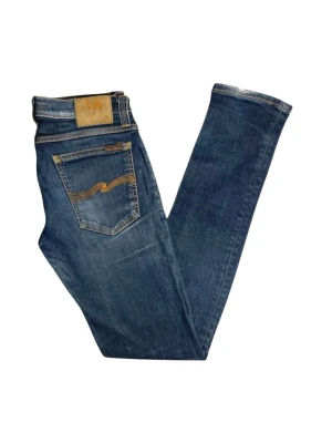 Blå slim jeans från Nudie Jeans 2x - Säljer ett par klassiska blå jeans från Nudie Jeans med slim passform. Jeansen har snygga detaljer på bakfickorna och är tillverkade i bomull. Perfekta för dig som gillar en enkel men stilren look.