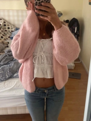 Ljusrosa fluffig kofta - Mysig ljusrosa kofta med oversized passform och ballongärmar. Koftan är stickad i ett fluffigt material som ger en trendig och avslappnad look. Perfekt att slänga över en topp för en söt och chill outfit.