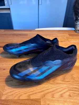 Adidas fotbollsskor - Säljer ett par svarta fotbollsskor från Adidas med blå detaljer och klassiska tre ränder på sidan. Det är storlek 40 1/3. Det är högsta verisionen på skorna alltså är det högsta kvaliteten man kan ha