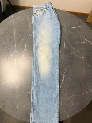Ljusblå raka Diesel jeans - Säljer ett par ljusblå Disesel jeans med raka ben och klassisk femficksdesign. Jeansen har slitningar och en snygg tvätt med ljusare partier framtill. Tillverkade i bomull med metallnitar.