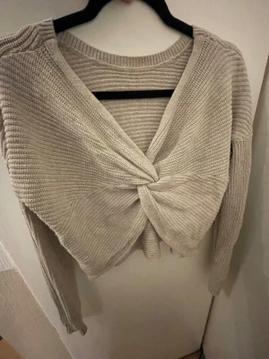 Beige twistad stickad tröja - Trendig beige stickad tröja .  Långärmad modell i mjukt material som ger en avslappnad men snygg look. Perfekt att styla med jeans eller kjol för en cool vardagsoutfit.
