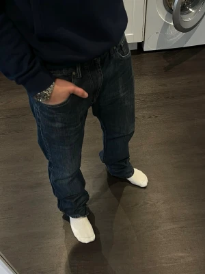 Schyssta Jeans från COF - Säljer ett par riktigt schyssta Jeans från Cottonfactory, som producerar jeans i höjd med Replay och Levis. De är i storleken 33/34. Jeansen har feta slitningar och gör sig perfekt till en någon som söker ett par lite schysstare jeans. Jeansen har en något bredare passform, klassiska fem fickor och coola kontrastsömmar. Bak och framfickan har snygga röda detaljer. Hör av dig vid minsta lilla fundering🙂