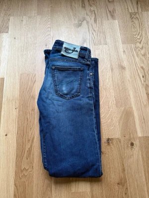 Blå jeans från Jacob cohen - Säljer ett par klassiska blå jeans från Jacob Cohen med raka ben och femficksmodell. Jeansen har en snygg tvätt med slitningar och Jacob Cohen logga bak. Perfekta för en avslappnad och trendig stil.