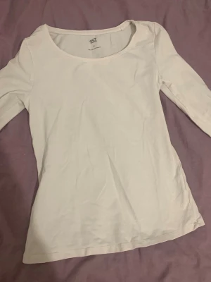 Vit långärmad topp från 157 - En basic vit långärmad topp från 157 med rund halsringning. Tillverkad i mjuk bomull, perfekt att styla till olika outfits. Enkel och stilren design som passar till mycket.