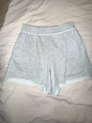 Grå sweatshorts  - Mysiga ljusgrå sweatshorts från Divided H&M med elastisk midja och avslappnad passform. Tillverkade i en mjuk blandning av bomull och polyester, perfekta för chill dagar eller träning.