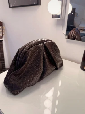 Mörkbrun clutch - Säljer en snygg mörkbrun clutch. Väskan har guldfärgade detaljer och svart innerfoder. Perfekt för dig som vill ha en trendig accessoar med lyxig känsla. Har aldrig kommit till användning!!🤎🤎