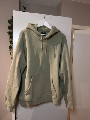 Khaki H&M hoodie  - En stilren khaki hoodie i oversized modell med stor känguruficka framtill och justerbar huva med snören. Mjuk bomullskänsla och ribbade muddar vid ärmslut och nederkant. Perfekt för en avslappnad och trendig look.