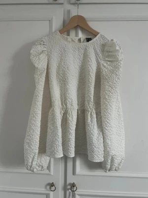 Vit strukturerad blus med puffärm - Supersnygg vit blus med strukturerat tyg och voluminösa puffärmar. Rund halsringning och markerad midja som ger en feminin siluett. Köpt för 600kr 