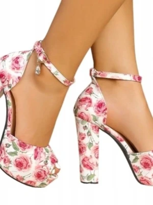 Blommiga platåpumps med ankelrem - Säljer ett par vita pumps med rosa rosor och gröna blad, platå och bred klack. Skorna har öppen tå och justerbar ankelrem med liten hängande dekoration. Perfekta för dig som vill sticka ut med ett romantiskt och färgglatt mönster.
