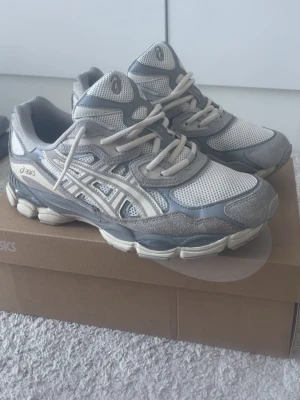 Asics gel-nyc  - Snygga sneakers från Asics i modellen Gel-nyc cream/oyster grey med mesh- och mockadetaljer. Har använt de 3 ggr och säljer för ett bättre pris än det originala. Meshet har ändrat lite färg och blev rufsig pga av snö.