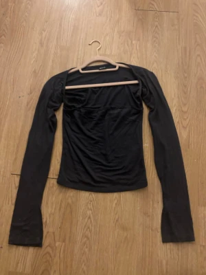 Svart långärmad topp från Gina Tricot - En svart, figurnära långärmad topp från Gina Tricot. Toppen har en enkel och stilren design och mjukt stretchigt material som sitter snyggt på kroppen. Perfekt att matcha med jeans eller kjol.