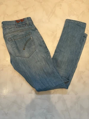 Dondup Jeans - Säljer ett par ljusblå jeans från Dondup  med klassisk femficksdesign och raka ben. Jeansen har diskreta slitningar och en liten logga på bakfickan. Tillverkade i bomull med en skön passform som funkar till det mesta.