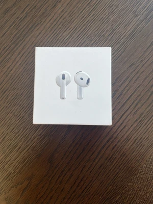 Apple AirPods trådlösa hörlurar - Säljer ett par vita Apple AirPods i originalförpackning. Snygg och stilren design med slimmad form, perfekt för dig som vill ha trådlösa hörlurar med grym ljudkvalitet. Passar till alla Apple-enheter och laddas enkelt i det medföljande fodralet.