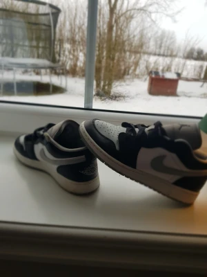 Air Jordan 1 Low svart/vit - Snygga Air Jordan 1 Low sneakers i svart och vitt läder med klassisk swoosh på sidan och Jumpman-logga på plösen. Skorna har svart snörning och låg siluett som ger en clean och sportig vibe. Perfekta för dig som gillar streetwear och ikoniska modeller. Skriv för frågor o funderingar 