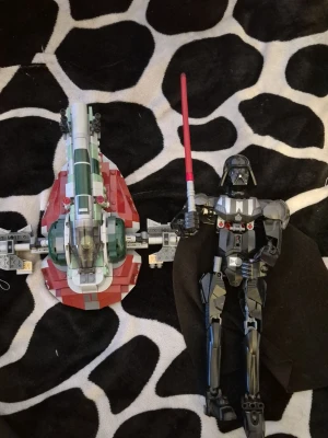 LEGO Star Wars Slave 1 och Darth Vader - Säljer ett LEGO Star Wars set med rymdskeppet Slave 1 i grönt, vitt och rött samt en byggbar Darth Vader-figur med svart cape och röd ljussabel. Perfekt för dig som gillar Star Wars och samlar på LEGO.