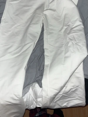 Vita mjukisbyxor  - Säljer ett par vita mjukisbyxor med avslappnad passform och dragsko i midjan. Byxorna är tillverkade i ett mjukt och bek sopmaterial, perfekta för chill dagar. Klassisk look utan synliga loggor eller detaljer. Helt nya