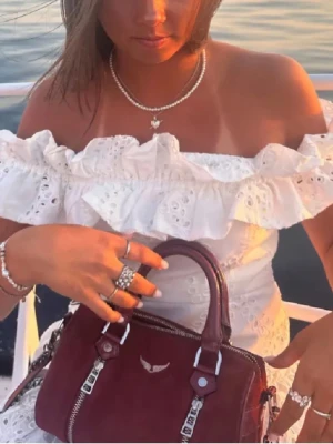 Väska från Zadig Voltaire  - Snygg vinröd handväska i skinn med silverfärgade dragkedjor och detaljer. Väskan har ett stilrent emblem framtill och både handtag och axelrem för olika sätt att bära. Perfekt accessoar för att lyfta din outfit.