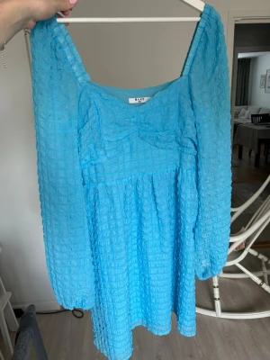 Sommarklänning NAKD - Väldigt fin och somrig blå klänning med fyrkantig urringning och luftiga långa ärmar. Storlek M. Knäpps på sidan. Väldigt bra skick. Från Na-kd.  ‼️OBS: testade klänningen och råkade spräcka innetyget🫣 Inget som syns, men går enkelt att laga med nål och tråd.