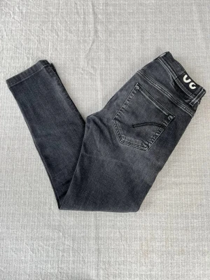 Svarta tvättade Dondup jeans, storlek 30 - Svarta stentvättade Dondup jeans, modell Konor i Skinny Fit. En stilren och modern jeansmodell från det italienska premiumvarumärket Dondup, perfekt för en tajt och välsittande silhuett.  Jeansen är i mycket bra skick. Enda anmärkningen är att lappen har försvunnit, i övrigt finns inga hål eller andra defekter.   Storlek: 30  Mått: 1/2 midja: 38 cm Längd: 98 cm Lårbredd: 24 cm                                                   Benöppning: 15 cm