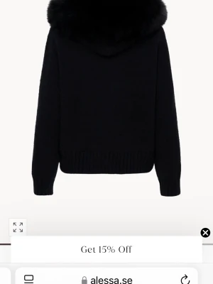 Svart jacka med pälskrage - Stilren svart jacka med stor, fluffig pälskrage och ribbade muddar. Jackan har lång ärm och en klassisk, rak passform som passar perfekt till kyligare dagar. Materialet ser mjukt och varmt ut, vilket gör den både snygg och bekväm. Jackan är i lite tjockare stickat material, vilket gör att du kan använda den på vintern också, jackan är knappt använd med äkta päls! Pris diskuteras vid snabb affär! 