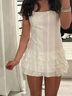 Vit volangklänning från zara - Supersöt vit klänning med volangdetaljer nertill och raka axelband. Klänningen har en enkel, rak passform och är perfekt för sommarens alla tillfällen. Tillverkad i ett lätt tyg som ger en luftig känsla.